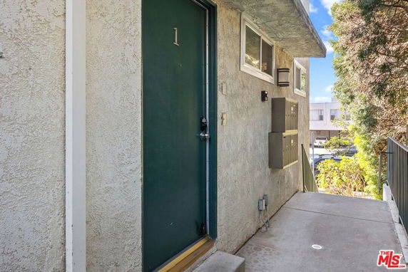 Exterior view of a building entrance with a green door and numbered sign.