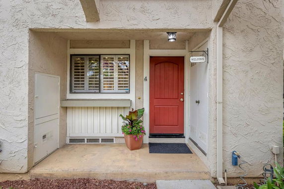Front entrance of a house with a red door and textured walls.