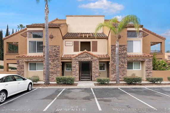 Front view of a residential building with stone accents and tan stucco exterior.