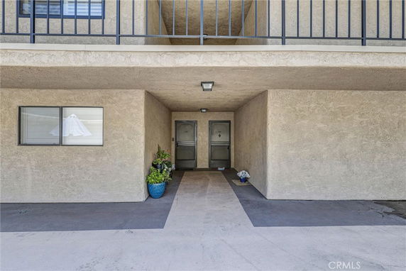 Entrance view of a building with two doors and a window, covered with a balcony above.