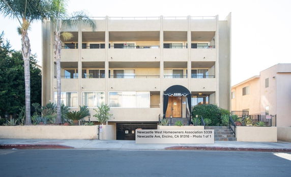 Front view of a multi-story residential building with a central entrance and balconies.