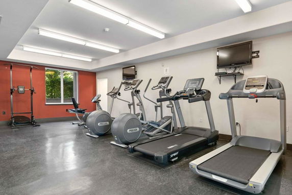 Indoor gym area with exercise equipment including treadmills and weight machines.