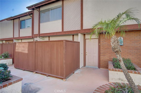 Front view of a two-story building with a wooden fence and a small courtyard area.
