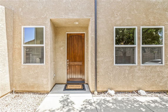 Entryway of a house with a wooden door and two windows.
