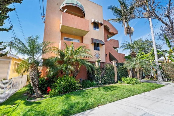 Front view of a multi-story house with distinctive architectural design and awnings.