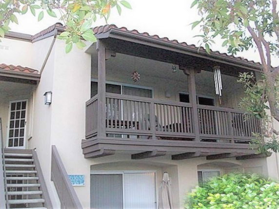 Front view of a two-story house with a covered balcony and exterior staircase.