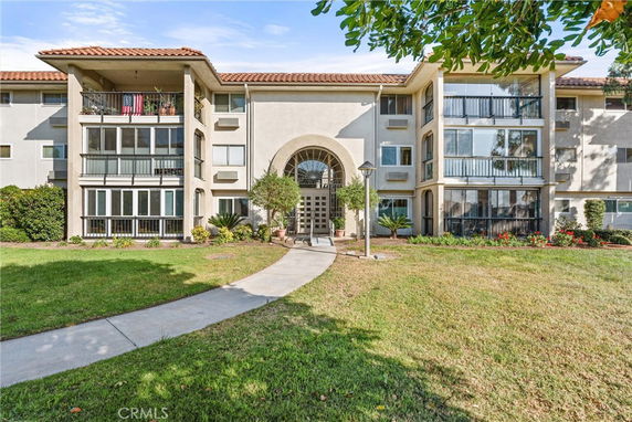 Front view of a multi-story residential building with balconies and a central arched entrance.