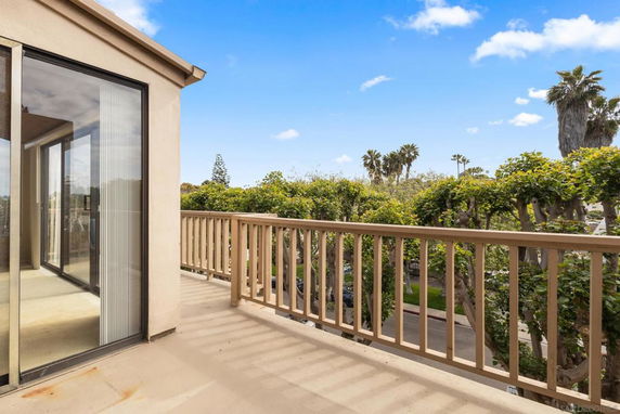 Balcony view with trees and blue sky.
