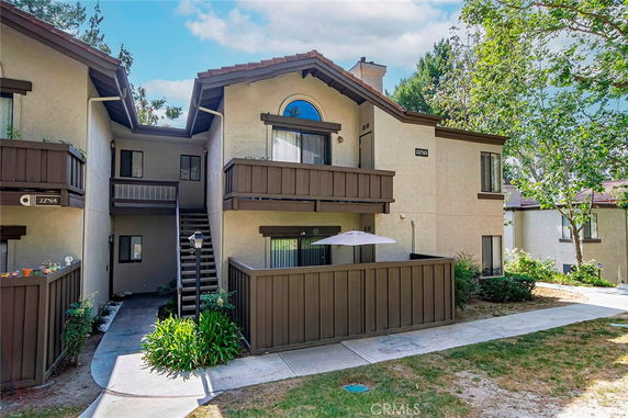 Front view of a two-story condominium with wooden balcony railings and exterior steps.