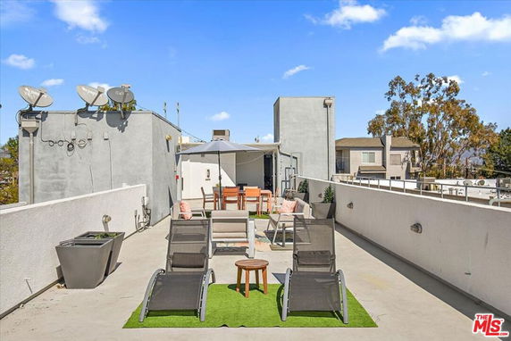 Rooftop seating area with lounge chairs, table, and umbrellas.