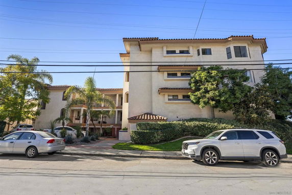 Front view of a multi-story building with balconies and a tiled roof.