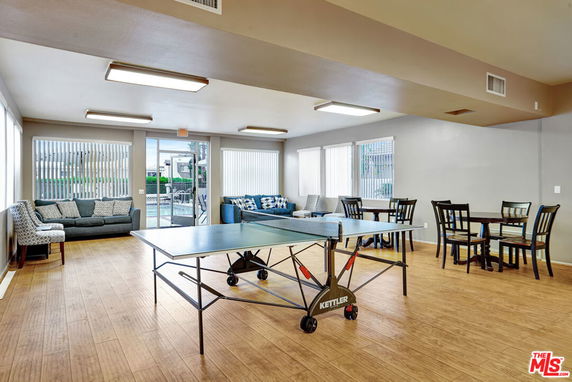 Room with a table tennis setup, seating area, and dining tables.