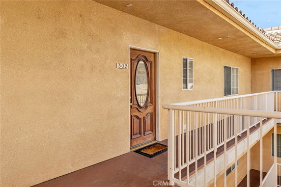 Exterior view of an apartment entrance with wooden door and railing.