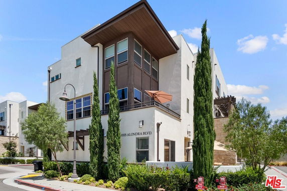 Front view of a modern multi-story building with large windows and a balcony.