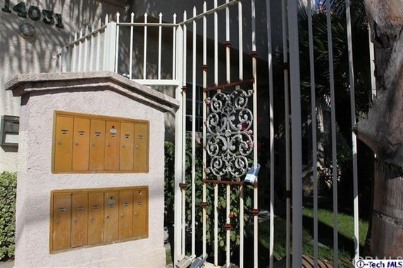 Front view of a building entrance with mailboxes and a decorative metal gate.