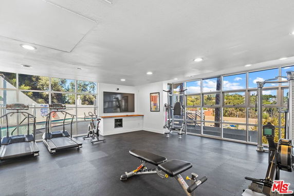 Interior view of a gym room with treadmills, exercise bikes, and weight machines.
