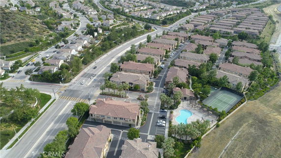 Aerial view of a residential area with multiple houses, a swimming pool, and a tennis court.