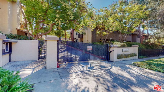 Front view of a gated residential building with trees.