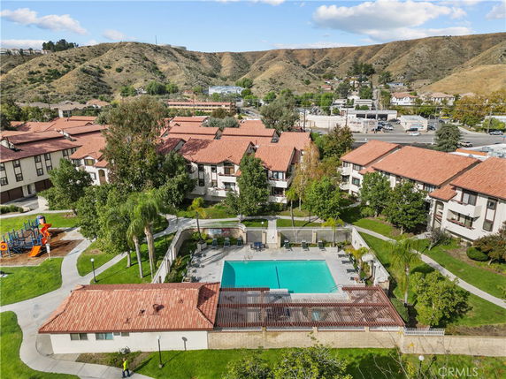 Panoramic view of a residential complex with a swimming pool and surrounding hills.