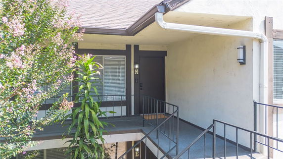 Front view of a house entrance with stairs and railing.