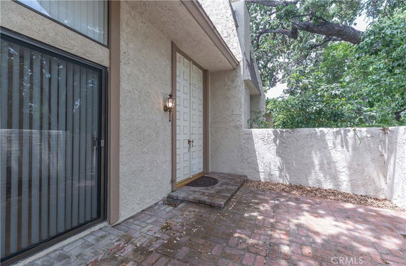 Front entry view of a house with a textured wall and brick walkway.