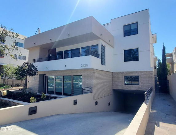 Front view of a modern three-story building with a flat roof and large windows.