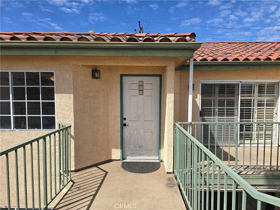 Front view of a building entrance with railing and tile roof.