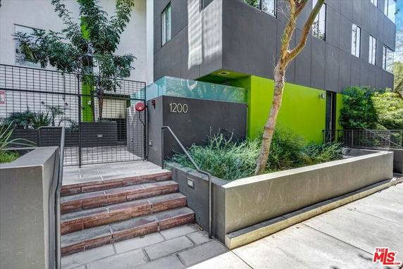 Entrance view of a modern multi-story building with green and gray facade.