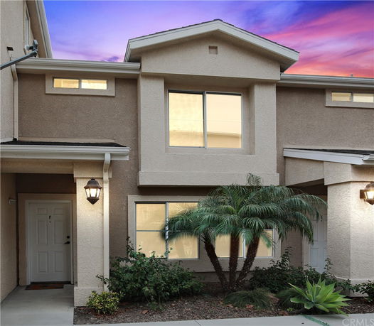 Front view of a two-story house with exterior lights and a small garden.