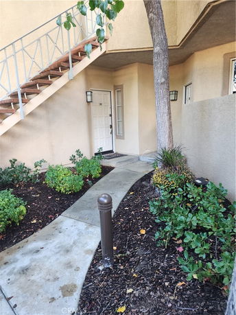 Front view of a building entrance with a staircase and a small garden area.