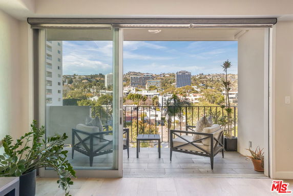 View from a balcony overlooking a cityscape with buildings and greenery.