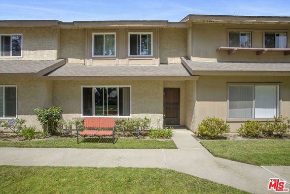 Front view of a two-story house with a wooden door and multiple windows.