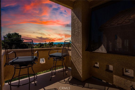 Balcony view with outdoor chairs overlooking a colorful sunset sky.
