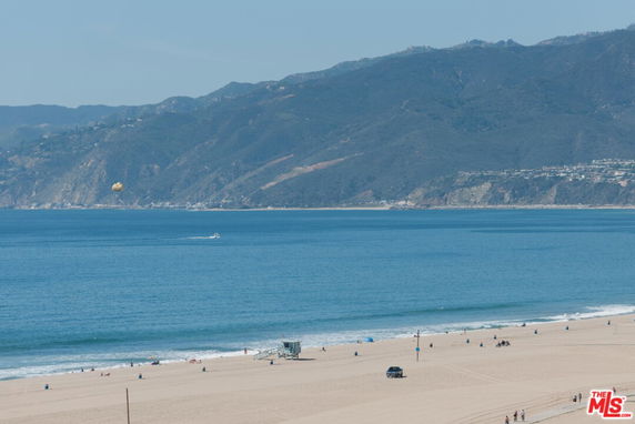 Panoramic view of a beach with a mountain backdrop and the ocean.