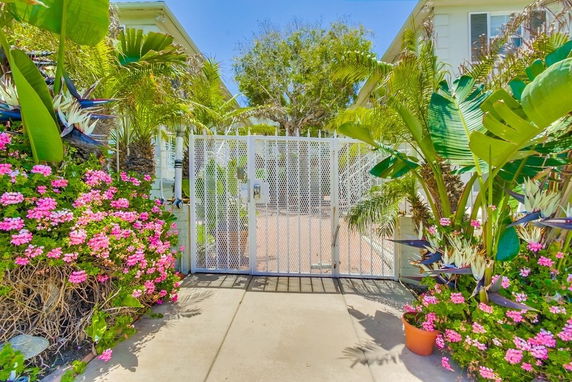 Front view of a house with a gate and surrounding greenery.