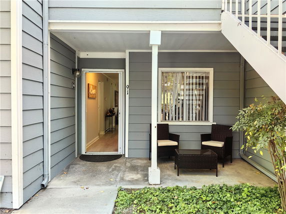 Front view of a house entrance with a small patio and seating area.