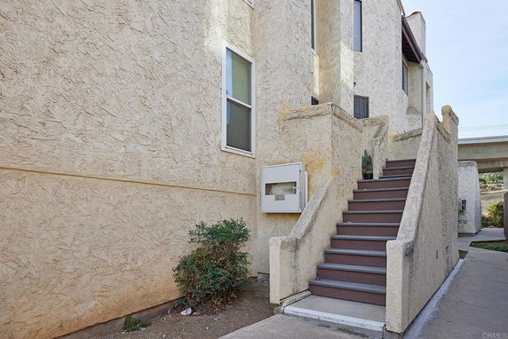 Front view of a beige multi-story building with an exterior staircase.