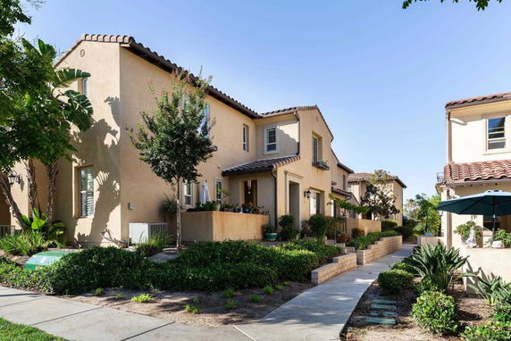 Front view of a multi-unit residential building with beige exterior and tile roofs.