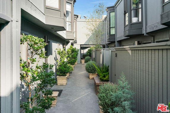 Exterior view of a modern residential building with a walkway and potted plants.