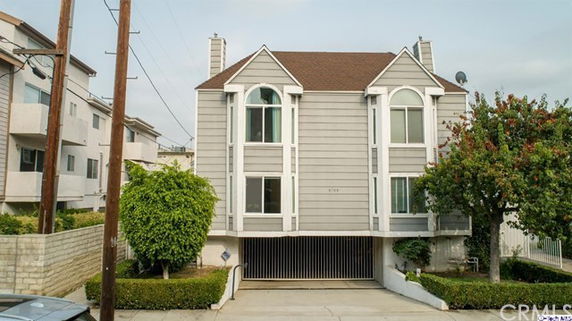 Front view of a multi-story house with a brown roof and large windows.