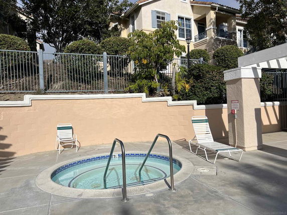 Outdoor jacuzzi area with lounge chairs in front of a residential building.