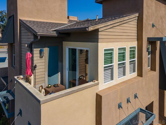 Rooftop area of a modern house with a small balcony and sliding glass door.