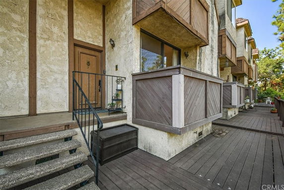 Front view of a multi-story building with wooden balconies and a staircase leading to the entrance.