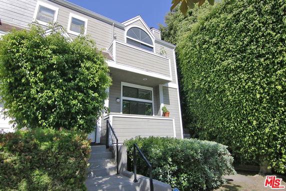 Front view of a two-story house with a balcony and entry steps.