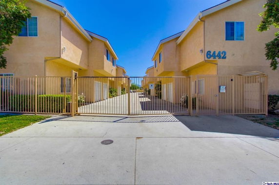 Front view of a gated two-story residential building with beige walls.