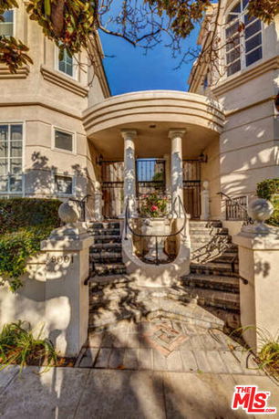 Front view of a house with a columned entrance and gated steps.