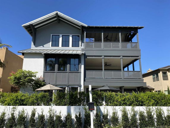 Front view of a three-story house with large windows and balconies.