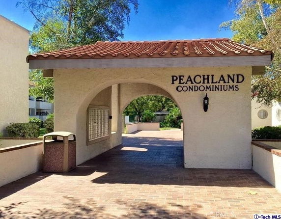 Front view of Peachland Condominiums entrance with archway and brick pathway.