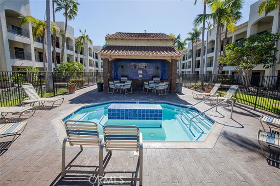 Outdoor swimming pool area with surrounding lounge chairs and a shaded sitting area.