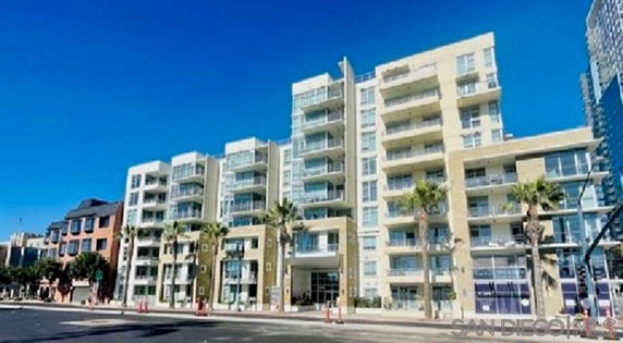 Front view of a multi-story apartment building with balconies and large windows.